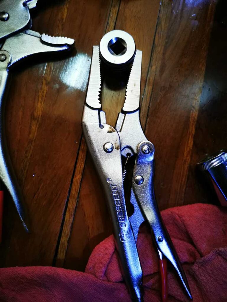 A nut in locking pliers ready to be inserted